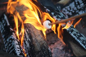 Roasting a marshmallow on a fire before zip lining at night at Canaan Zipline Canopy Tours near Rock Hill