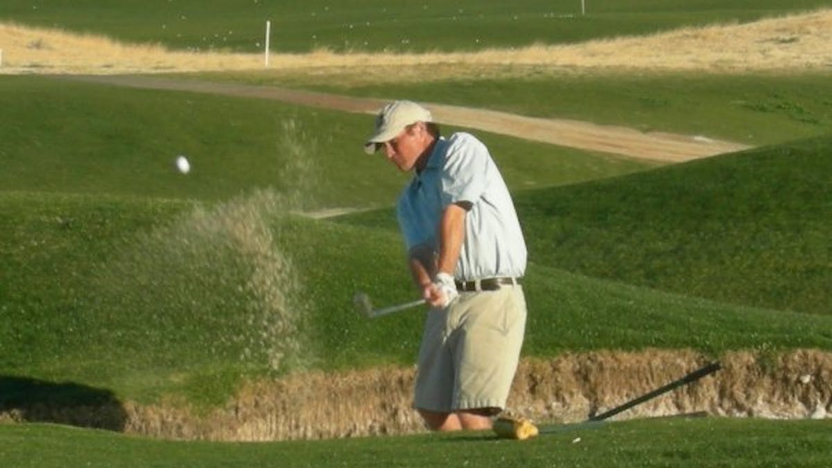man hitting ball out of sand trap