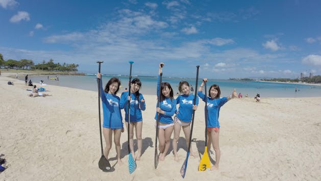 group of people standing on beach with paddles