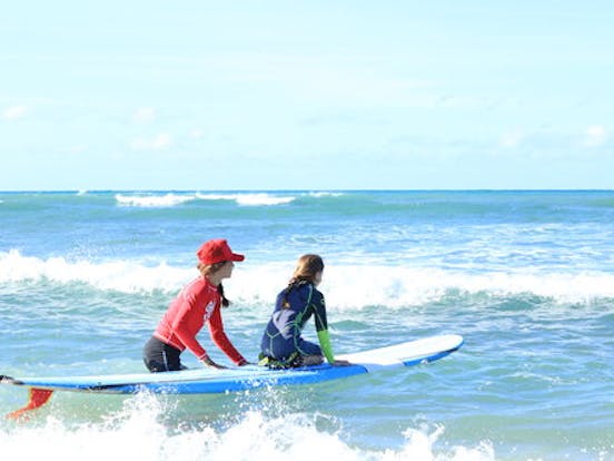 instructor walking with child and surfboard