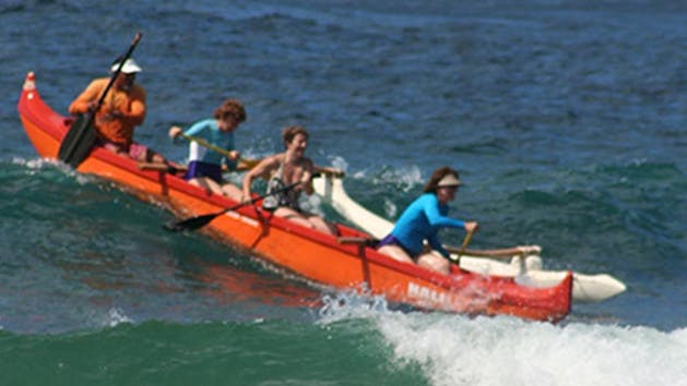 a group of people riding on the back of a boat in the water