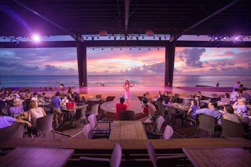 The sunset over the ocean as a performer plays the guitar at the Beach Bar & Grill in Tumon, Guam