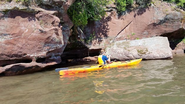 A person in a Kayak near the rocks