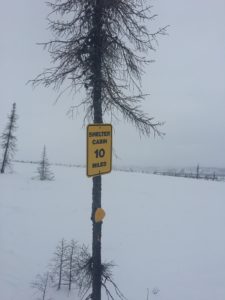 a pole that has a sign on the side of a snow covered street
