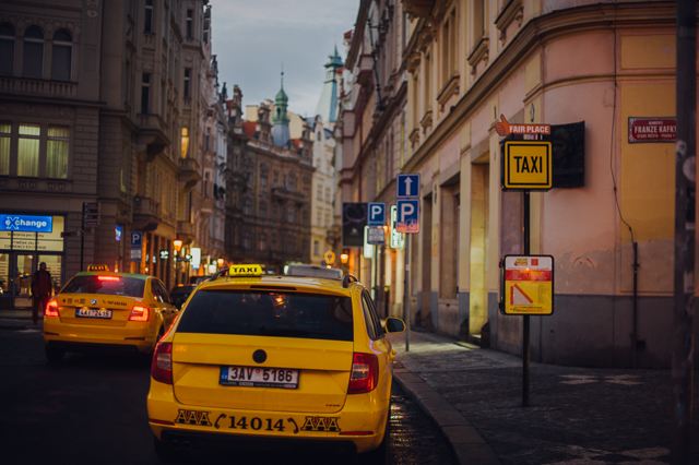 a yellow taxi in a street in Prague