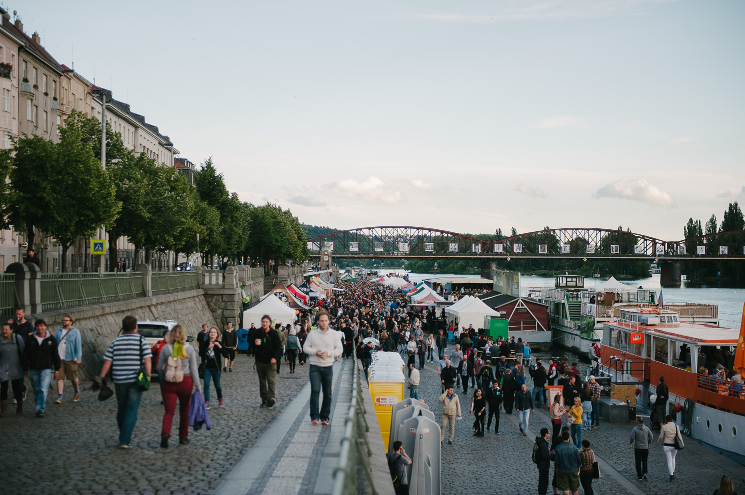 a crowd of people walking on Prague's Naplavka during a festival