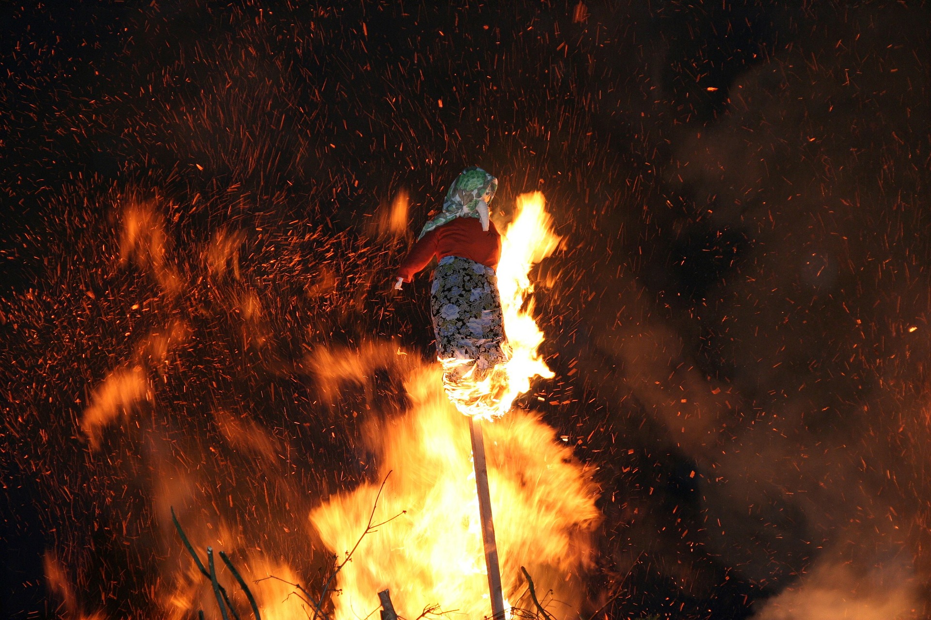 a bonfire with a witch made out of straw and broomsticks burning