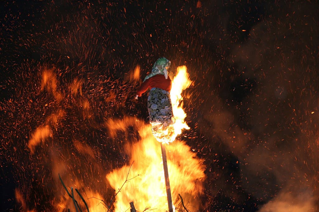 a bonfire with a witch made out of straw and broomsticks burning