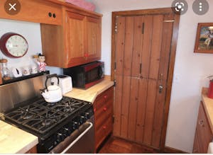 a kitchen with a stove top oven sitting inside of a wooden door