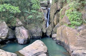 Waterfall in Yunque National Park called Rio Espiritu falling down into a body of water with a huge rock in the center