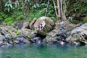 Man swinging into a river in puerto rico from a rock and a rope