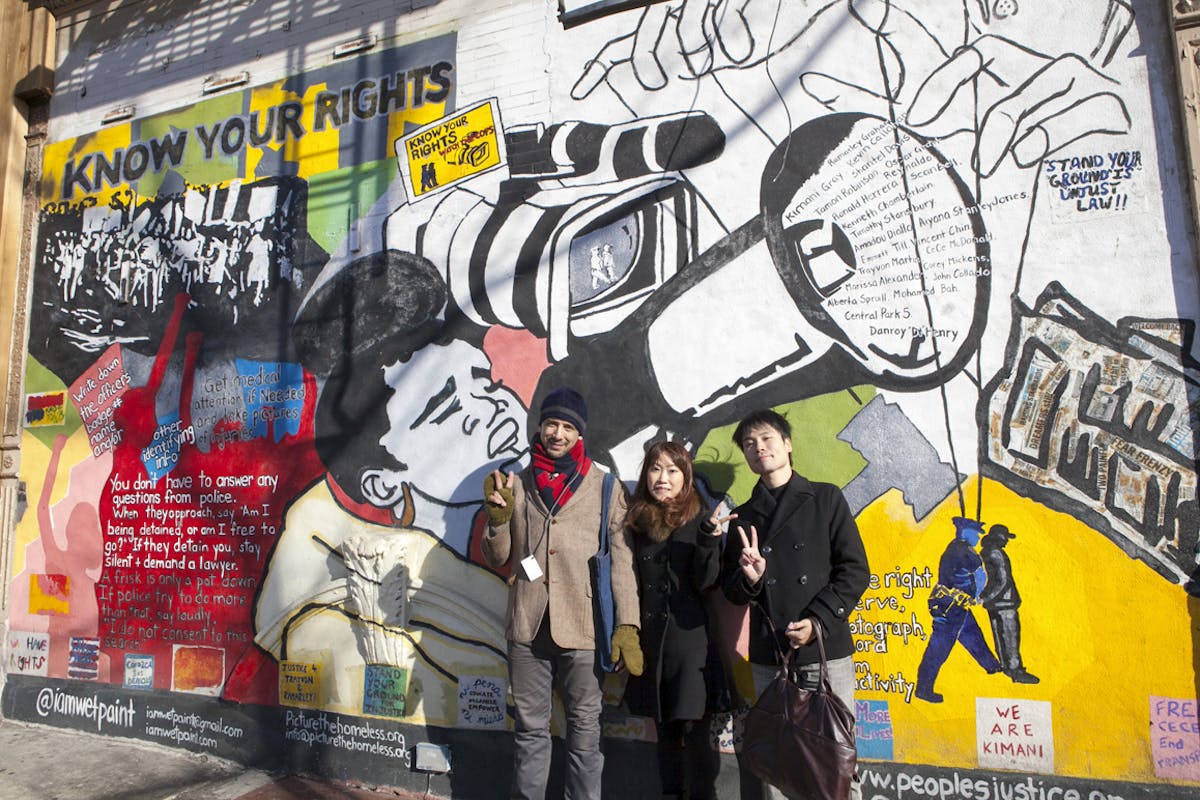 a group of people standing next to a graffiti covered wall