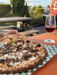 a pizza sitting on top of a table next to a glass of wine