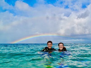 private scuba divers floating on the surface under a rainbow