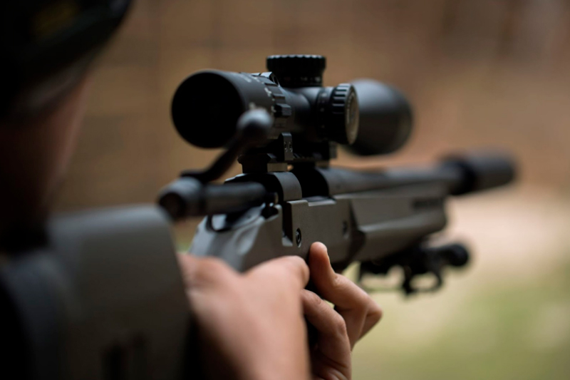 Man looking through scope of rifle