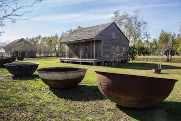 A few large bowls and an old cabin at the Whitney plantation during a whitney plantation tour