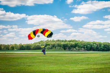 skydiver with parachute landing in a field