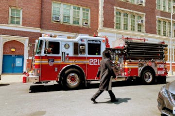 A firetruck in front of a building and a man walking in front of it