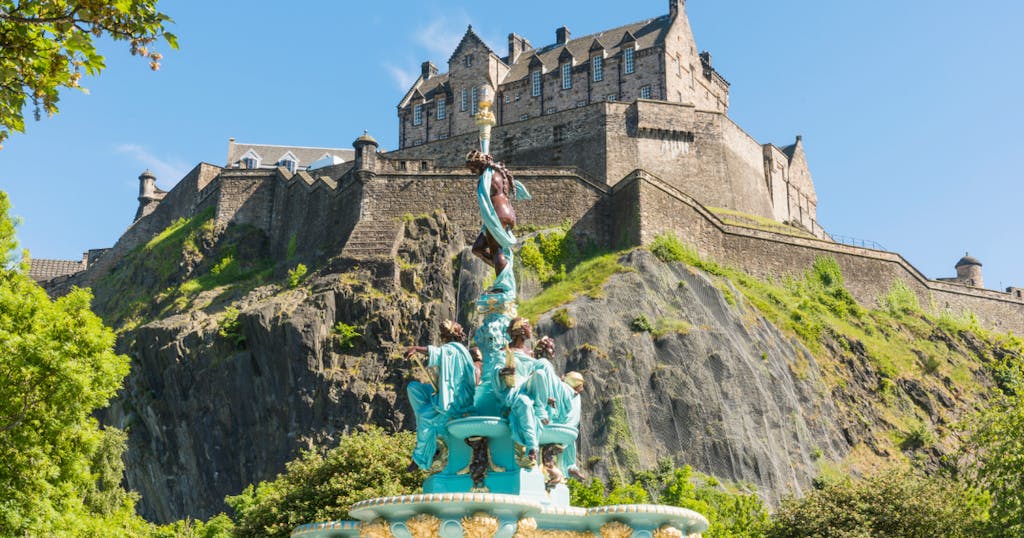 a large stone statue in front of a castle