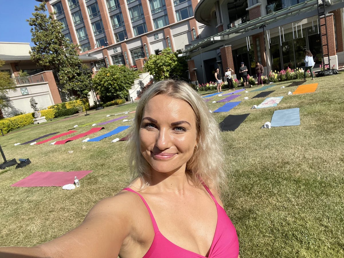 a blonde woman poses in front of a group of yoga mats in westlake