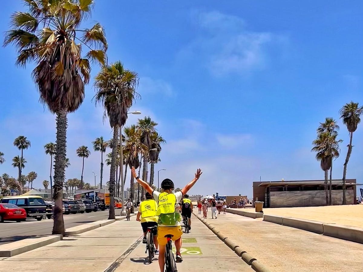 a group of people riding bikes down the beach in santa monica on a los angeles tour