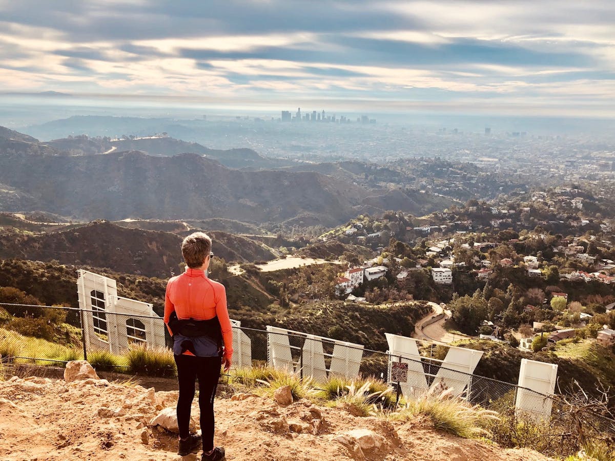 a hiker standing behind the hollywood sign on a hollywood sign tour