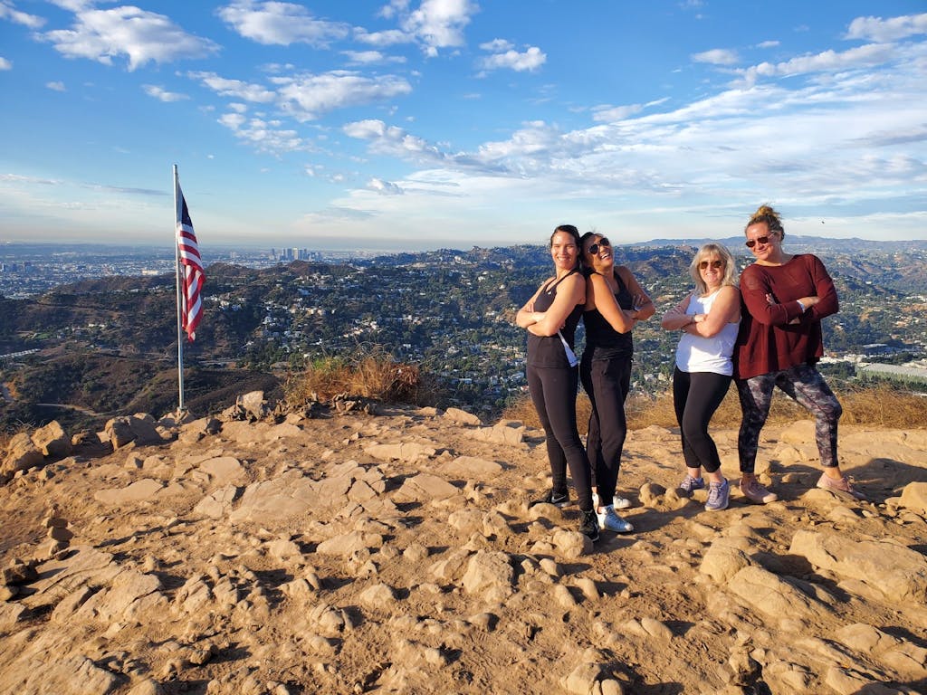 four girls pose by the american flag by the hollywood sign