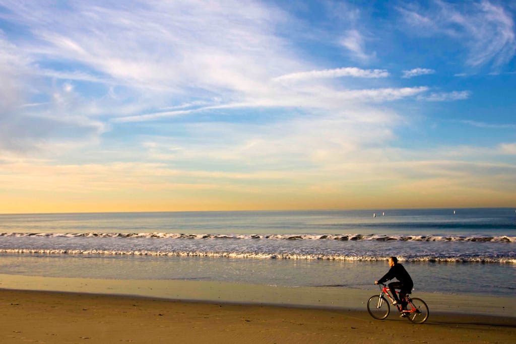 a man riding a bicycle on a beach