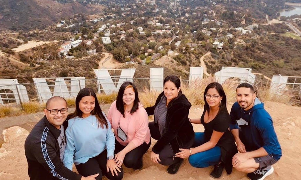 a group of people posing on a hike behind the hollywood sign