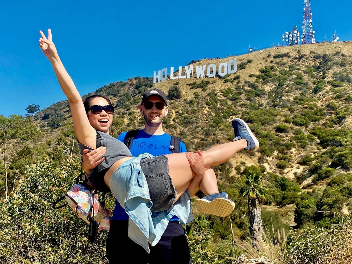 two people taking a hollywood sign tour in los angeles in front of the hollywood sign