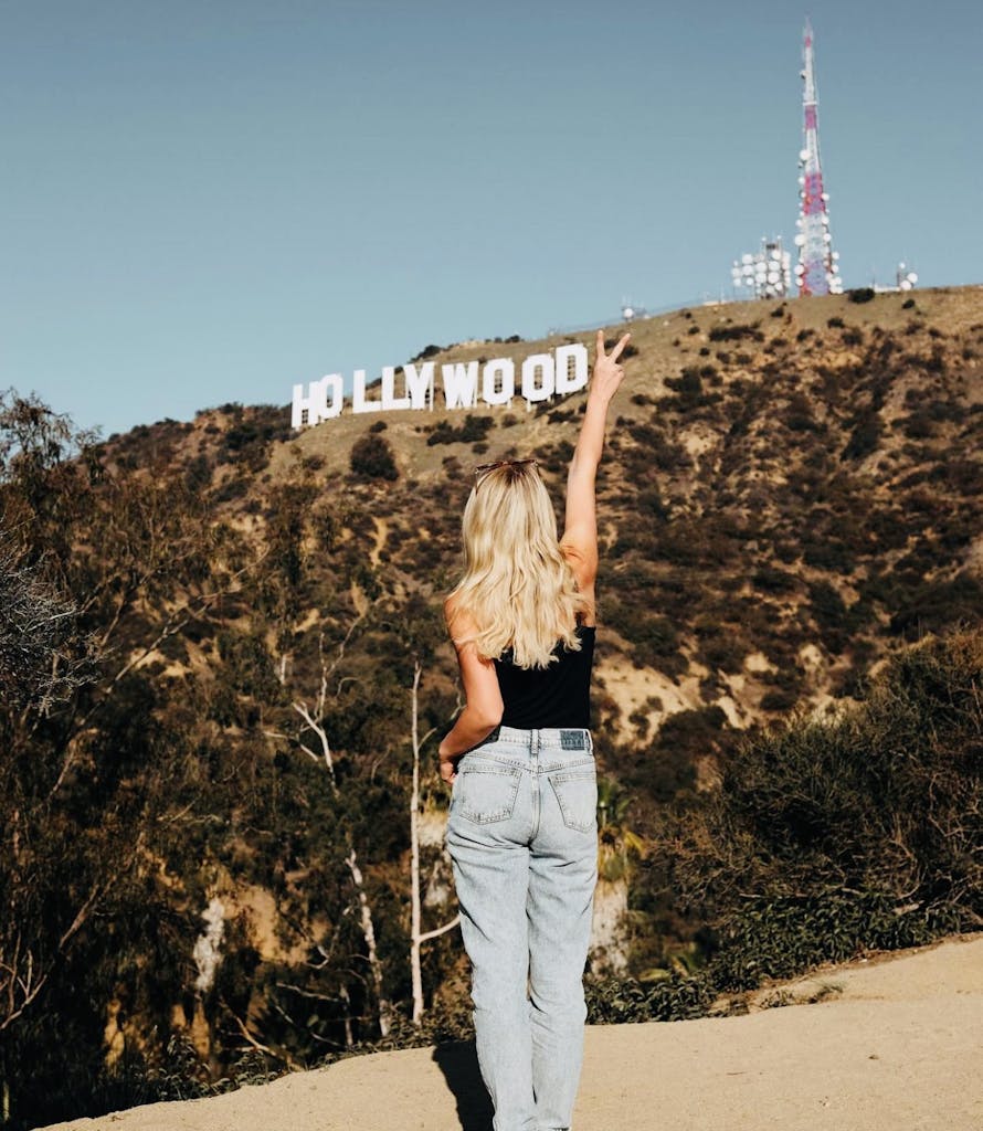 a woman standing in front of the hollywood sign with her back to the camera