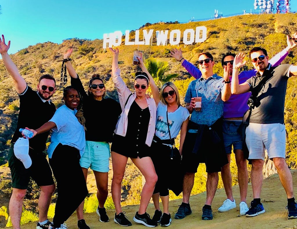 a group of people posing for a picture beneath the hollywood sign in los angeles