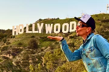 a man standing next to the hollywood sign