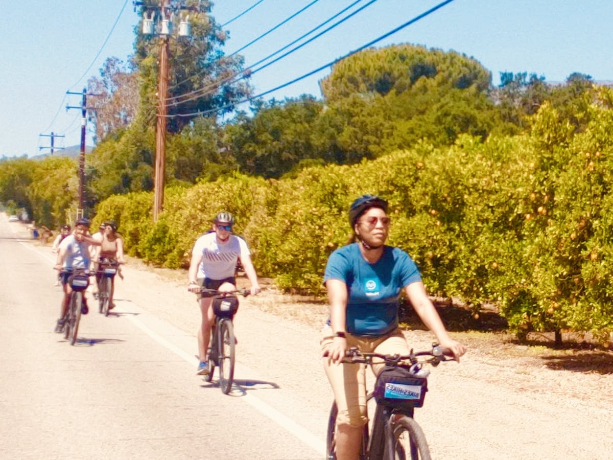 a group of people riding on the back of a bicycle on a street on an ojai tour