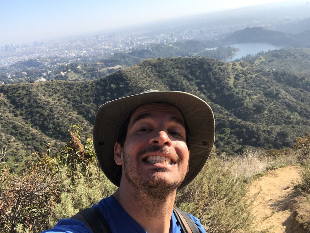 a man wearing a hat and a mountain in the background
