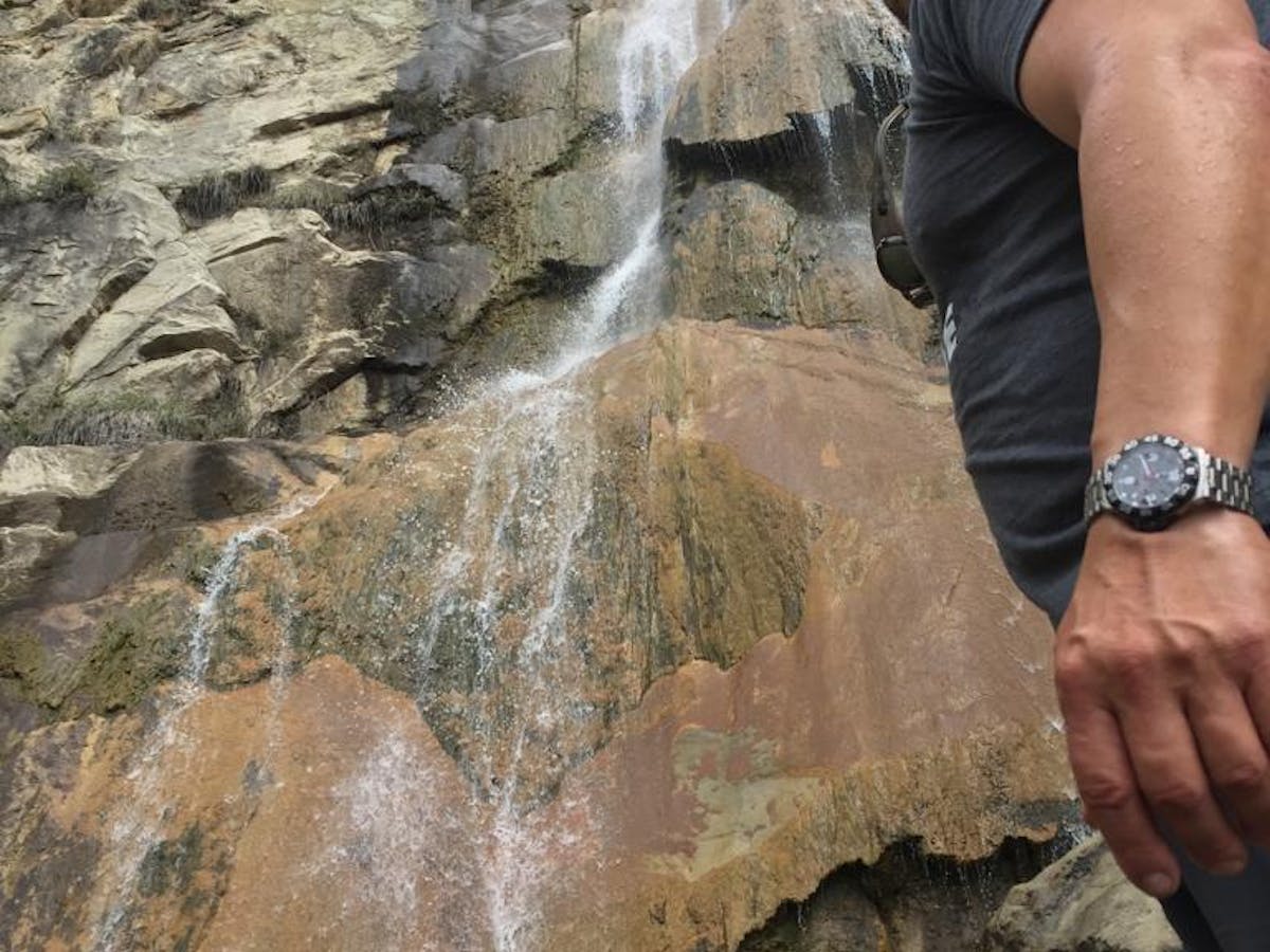 a person standing below a waterfall on a santa barbara group tour