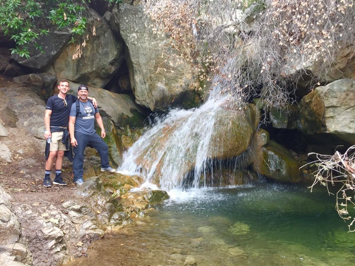 two guests standing next to a waterfall on a santa barbara group tour