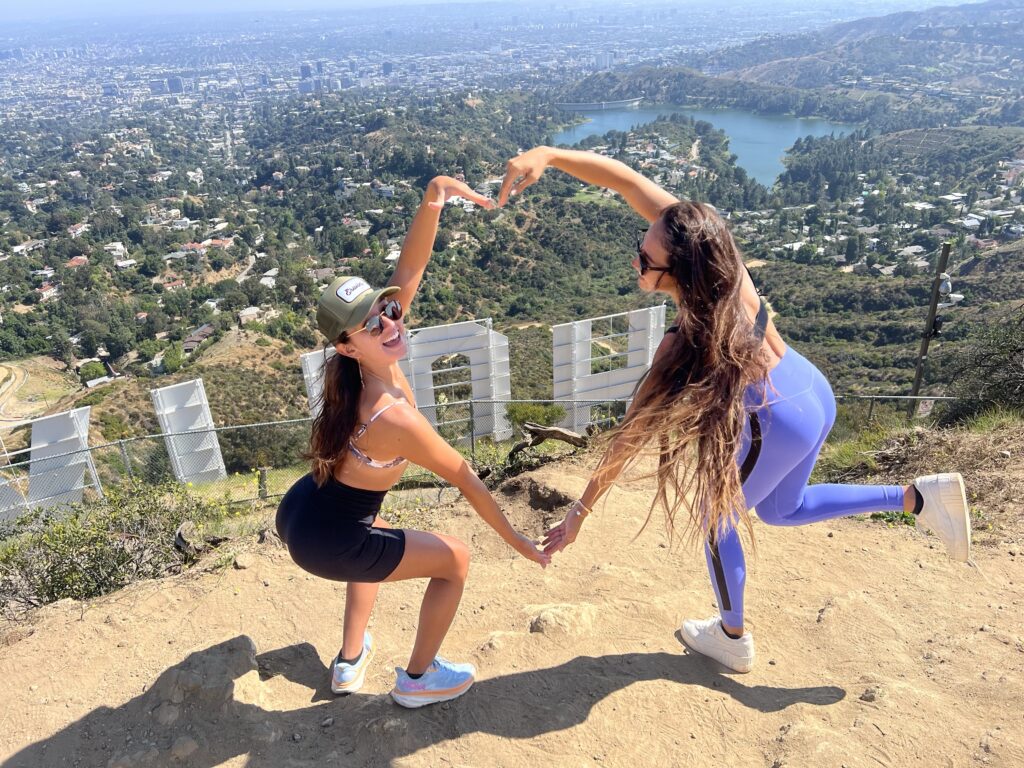 two guests making a heart with their arms behind the hollywood sign