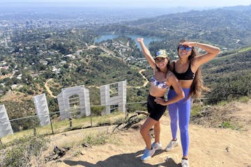 two guests standing on a mountain overlooking hollywood and los angeles on a hollywood sign hike