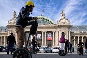 a man riding a motorcycle in front of Grand Palais