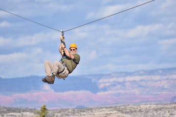A man zip lining with the Arizona valley and mountains in the background
