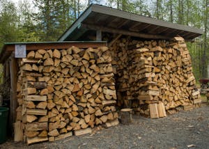 a pile of logs in front of a brick building