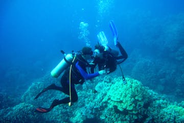 Two divers helping each other underwater