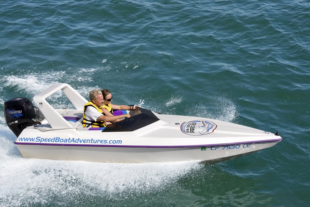 A couple drives in a private speed boat in a speed boat riding along the ocean in San Diego