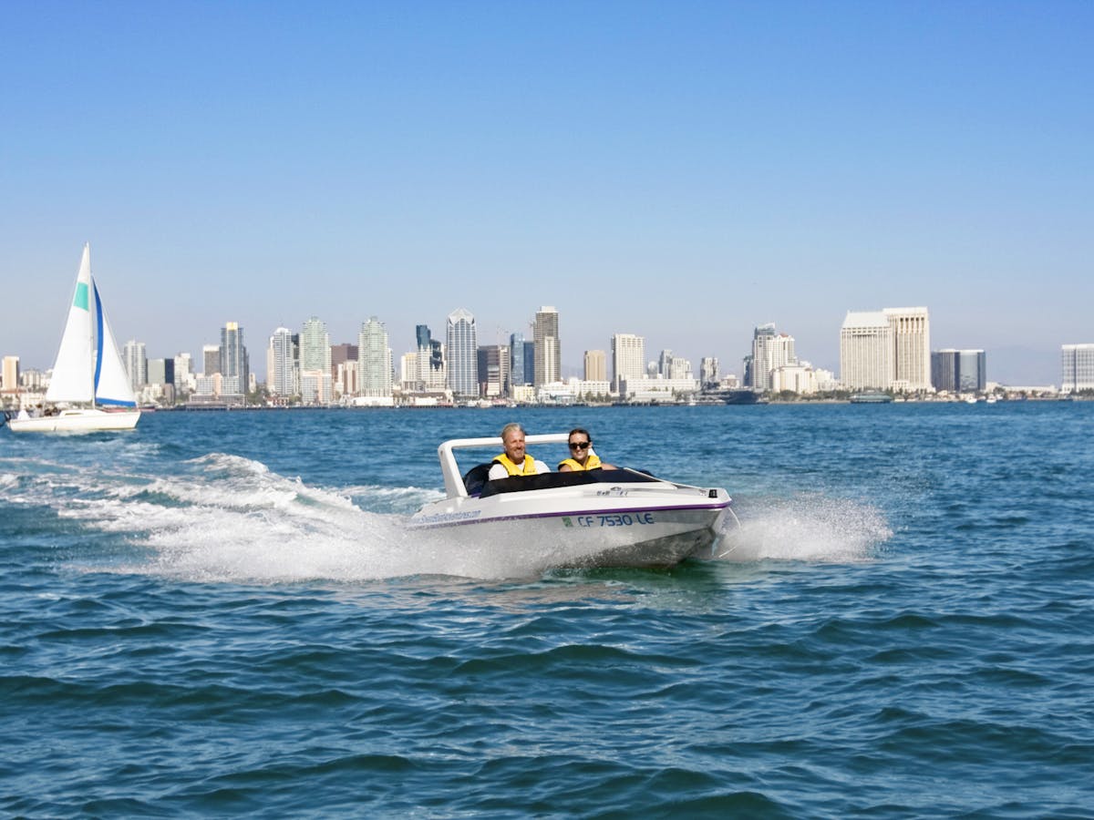 A driver and passenger in a speed boat in a speed boat riding along the ocean in San Diego