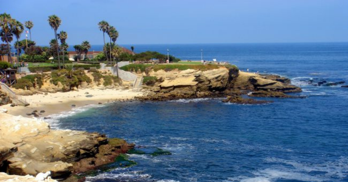 a rocky beach next to a body of water with La Jolla Cove in the background