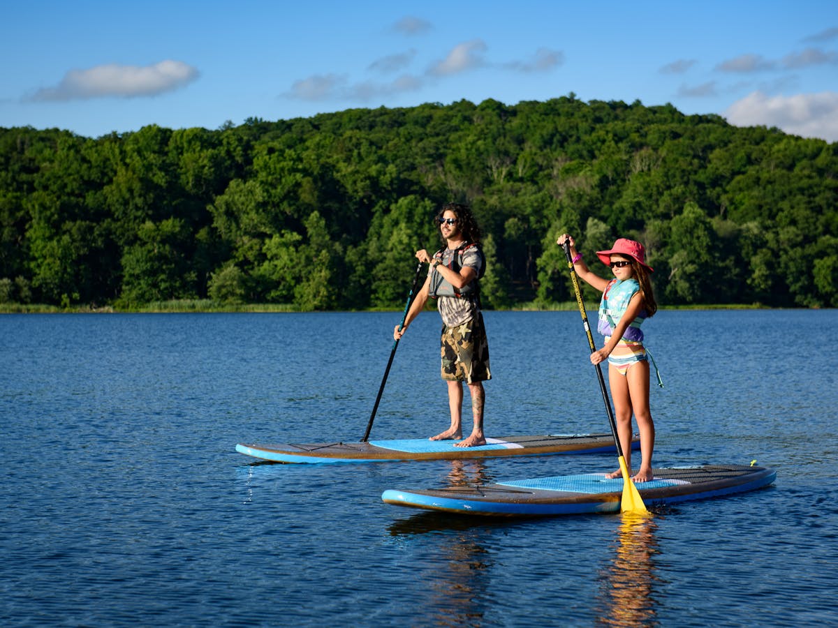 a father and daughter paddleboarding in a body of water