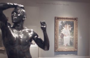 a statue of a man in the foreground with a photo of a woman and an angel on the wall in the background