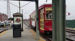 a streetcar stop with a red streetcar car to the right