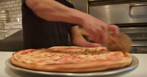 a person cutting a pizza
